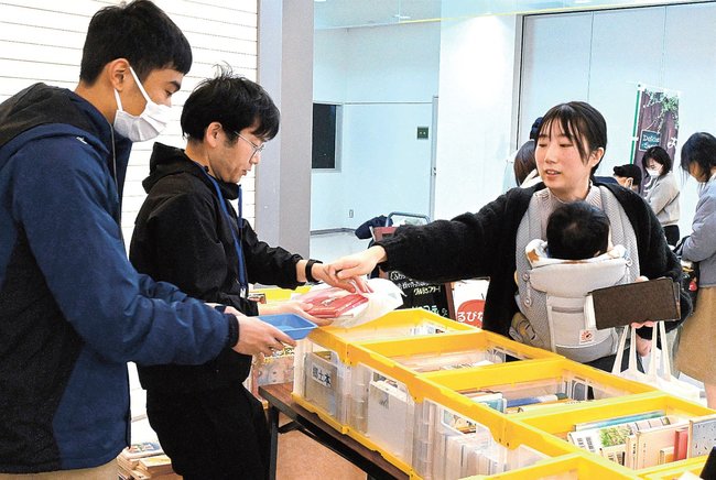 障害者がきれいにした古本を購入する参加者（右）＝松江市白潟本町、スティックビル