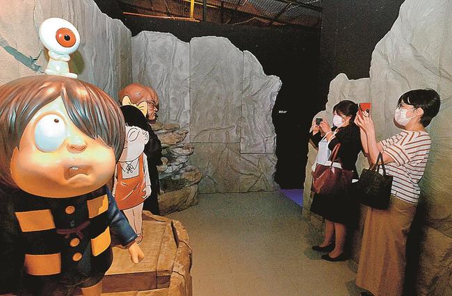 妖怪フィギュアを写真撮影する来場者＝境港市大正町、鬼太郎妖怪倉庫第三章