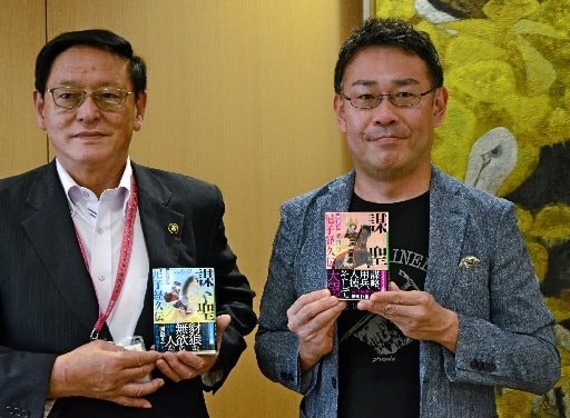 「謀聖 尼子経久伝」の第2弾「風雲の章」を手にする武内涼さん(右)。田中武夫市長が持つのは第1弾「青雲の章」=安来市安来町、市役所