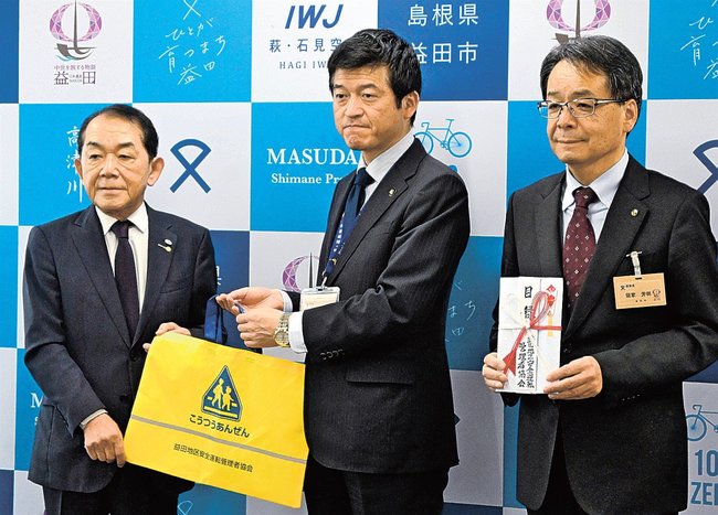 子どもを交通事故から守るかばんを受け取る山本浩章市長（中央）＝益田市常盤町、市役所