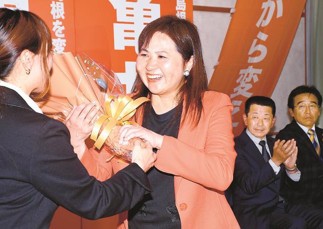 当選が確実となり、花束を受け取る亀井亜紀子氏＝２８日午後８時１８分、松江市御手船場町、労働会館