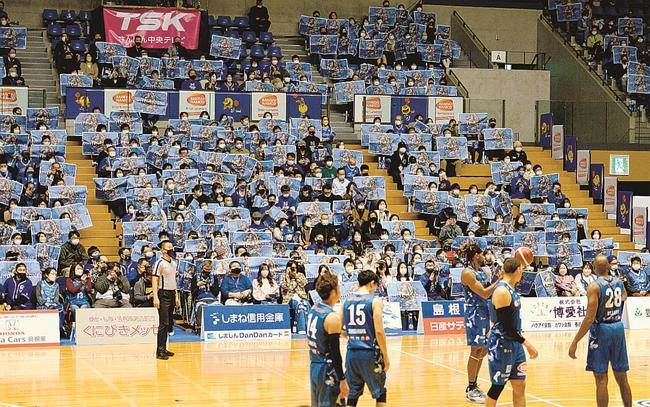 試合開始前、青色の特集紙面を掲げて応援する観客＝松江市学園南１丁目、松江市総合体育館