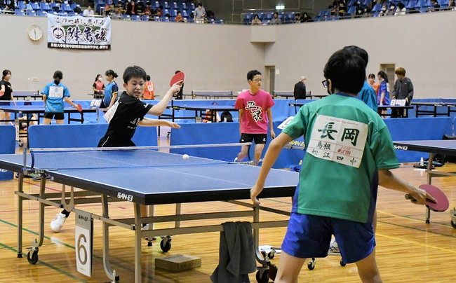 スマッシュを打つ選手（左）＝松江市鹿島町佐陀本郷、鹿島総合体育館
