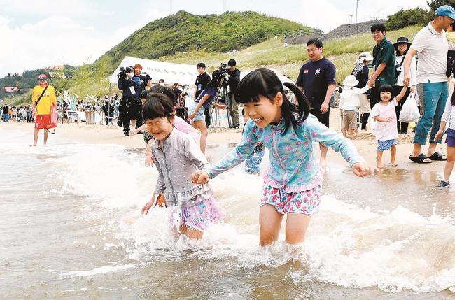 海開きした「キララビーチ」の波打ち際で遊ぶ子どもたち＝出雲市多伎町多岐、岐久海岸海水浴場