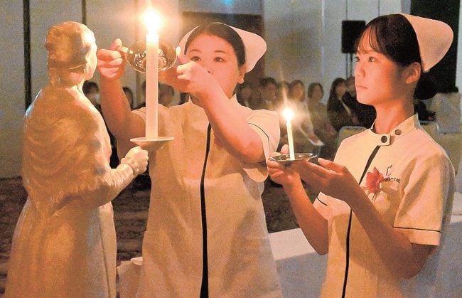 ろうそくに灯を移す学生＝出雲市今市町、ラピタウェディングパレス