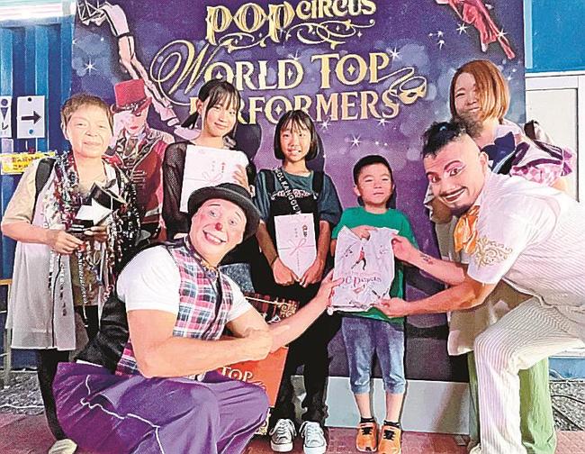 １万人目の来場者となり、クラウンに囲まれる川村吏巧くん（右から３人目）＝松江市学園南１丁目、旧島根県立プール跡地特設大テント