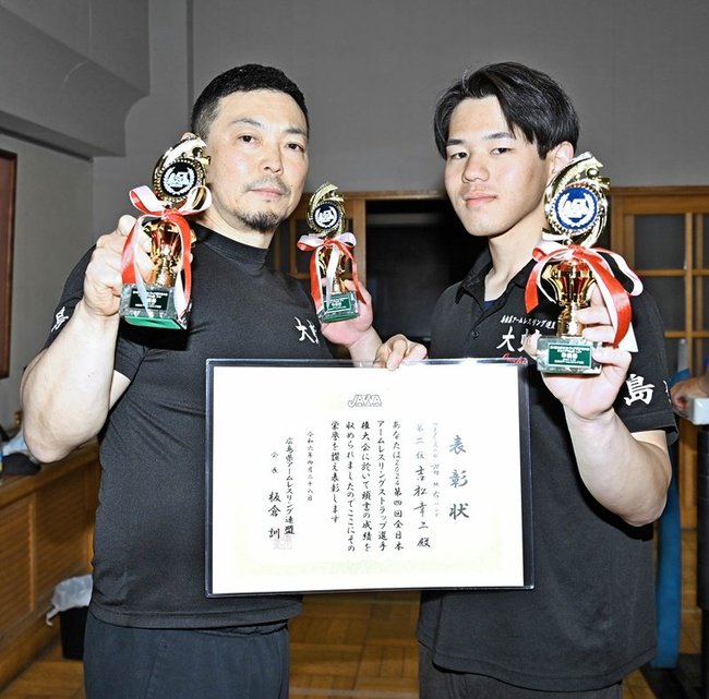 表彰状とトロフィーを手にする吉松幸二さん（左）と両手にトロフィーを持つ岡田悠さん＝益田市中吉田町、吉田小学校