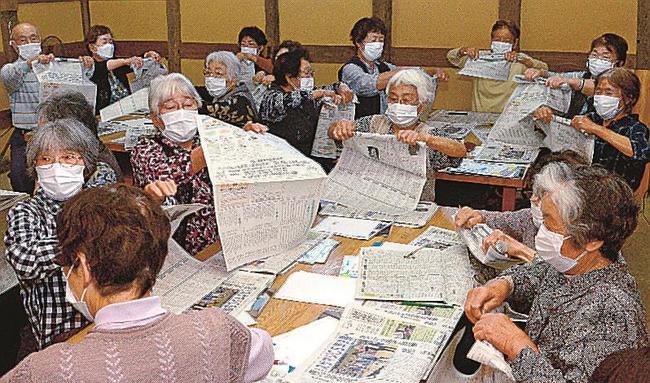 本紙を指先で巻き上げる参加者＝大田市大代町、大江高山きずな館