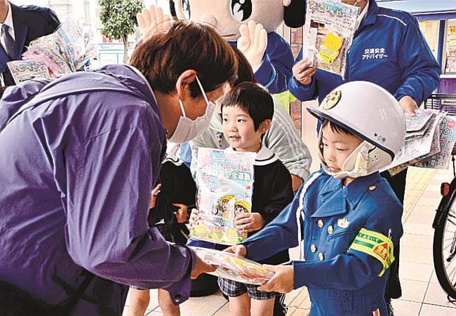 買い物客（左）に啓発グッズの入った袋を手渡す園児＝浜田市港町、ゆめタウン浜田