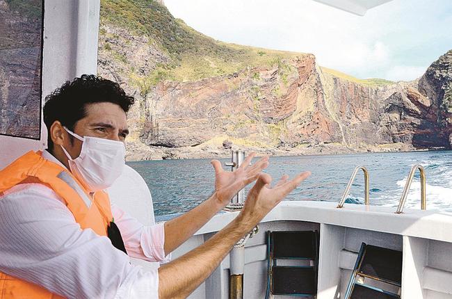 知夫里島遊覧の「べんてん丸」船上で赤壁の成り立ちをガイドするゴメス・ダヴィッドさん＝島根県知夫村