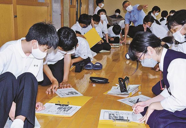 新聞記事を読んで見出しを考える生徒＝松江市鹿島町名分、鹿島中学校