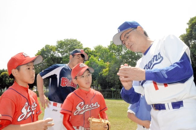 雲南市であった野球教室で、児童に正しいボールの握り方を教える三沢淳さん（右）（資料）