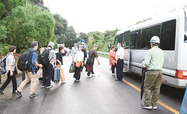 徒歩で崩落現場を迂回（うかい）し、迎えのバスに乗り込む観光客＝１０日、出雲市大社町日御碕