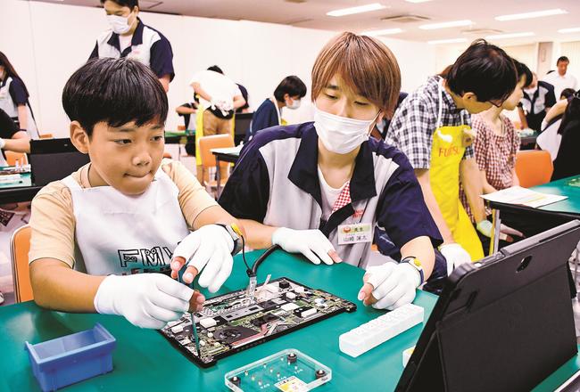 慎重にノートパソコンのねじ締め作業をする参加者＝出雲市斐川町三絡、島根富士通