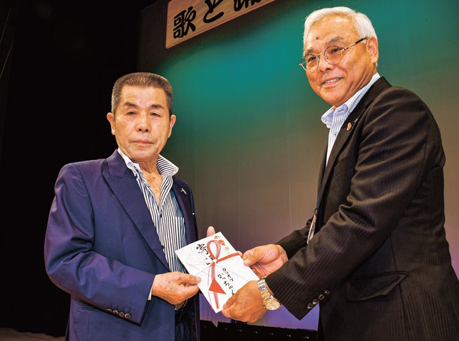 寄付の目録を末成弘明会長（右）に手渡す火脚勝人さん＝益田市美都町都茂、ふれあいホールみと