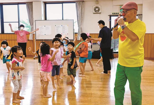 園児たちの前で演奏する吾郷孝彦さん（右）＝浜田市浅井町、聖バルナバ保育園