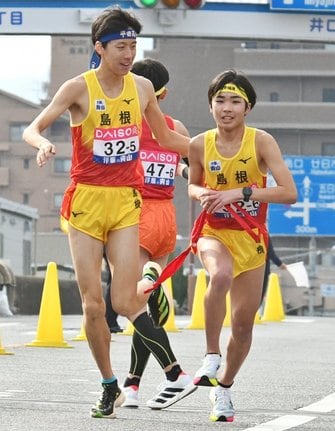 ５区岩崎輝翔（左）からたすきを受けて走り出す６区佐古隼磨