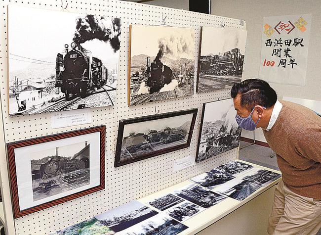 西浜田駅を出発する蒸気機関車の写真を見る来場者＝浜田市熱田町、長浜まちづくりセンター