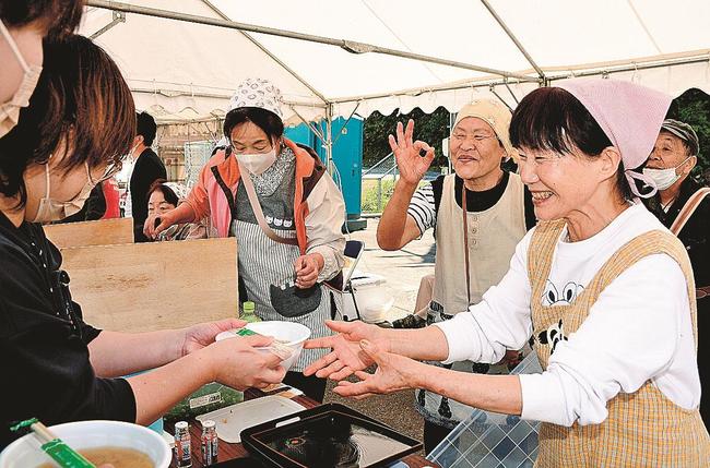 里芋を使った汁物を来場者に提供する住民ら＝浜田市弥栄町三里、ふるさと体験村