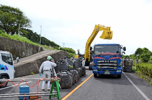 路面の隆起や崩落現場付近で復旧工事の準備を進める建設業者＝出雲市多伎町小田、国道９号