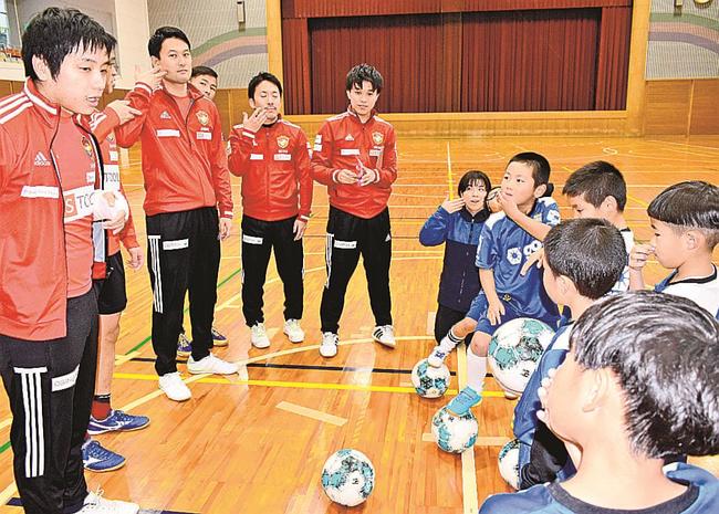 デフフットサルの選手（左側）からジェスチャーを教わる子どもたち＝浜田市金城町七条、ふれあいジムかなぎ