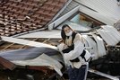 石川県珠洲市で変わり果てた町の様子を不安そうに見つめる女性。地震で家の中がめちゃくちゃになり、２歳と０歳の子と避難所に身を寄せる。「夜になると子どもは怖いみたいです。周りの人の助けがありがたいです。ミルクやおむつが続くかなど不安は尽きません」＝４日午前９時