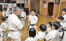 豊田篤志館長（左）から、筋肉の働きについて仲間たちと学ぶ石橋汰壱君＝益田市高津２丁目、高津武道館
