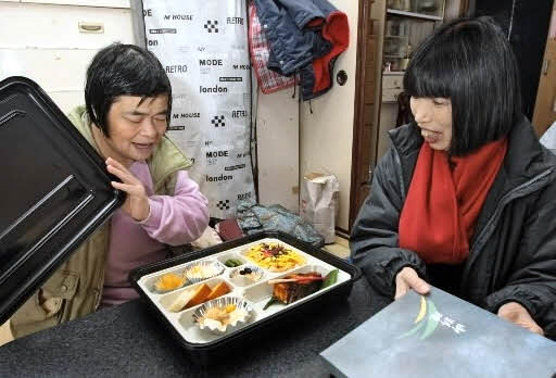 復興住宅の被災者におせち料理を届ける黒田裕子さん(右)=神戸市内、2008年(宇都幸子提供)
