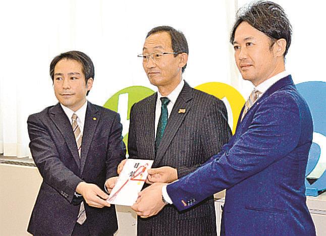 寄贈図書の目録を受け取る足羽英樹教育長（中央）。左は山陰中央新報社の福間崇広鳥取総局長、右は山陰中央テレビジョン放送の佐藤成興鳥取総局鳥取統括支社長＝鳥取市東町１丁目、県庁