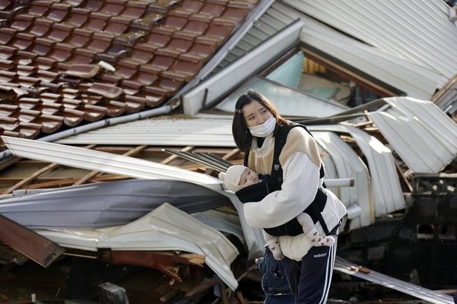 石川県珠洲市で変わり果てた町の様子を不安そうに見つめる女性。地震で家の中がめちゃくちゃになり、２歳と０歳の子と避難所に身を寄せる。「夜になると子どもは怖いみたいです。周りの人の助けがありがたいです。ミルクやおむつが続くかなど不安は尽きません」＝４日午前９時