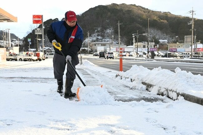 店周辺の除雪作業をする国道５４号沿いのガソリンスタンドの従業員＝５日午前７時５１分、雲南市木次町里方
