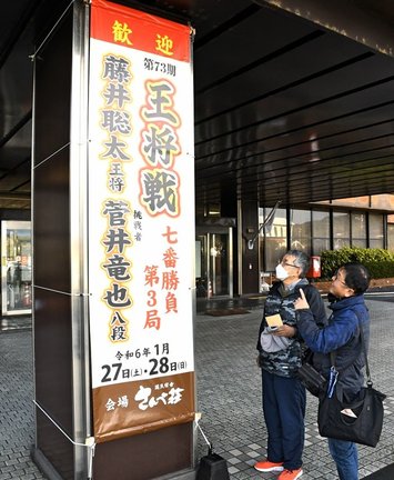 王将戦第３局の開催を伝える懸垂幕を見る市民＝大田市大田町、市役所