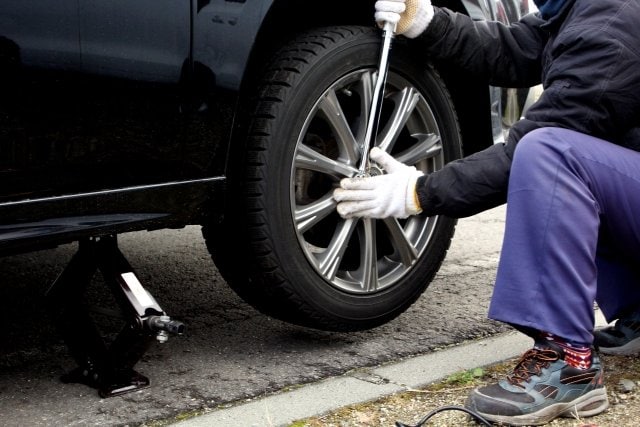 車のタイヤ交換でナットを締めている様子（資料）