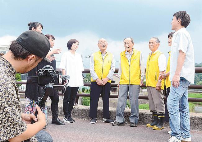 撮影に臨む雲南せいねんだんと、赤川ほたる保存会のメンバーたち＝雲南市大東町内