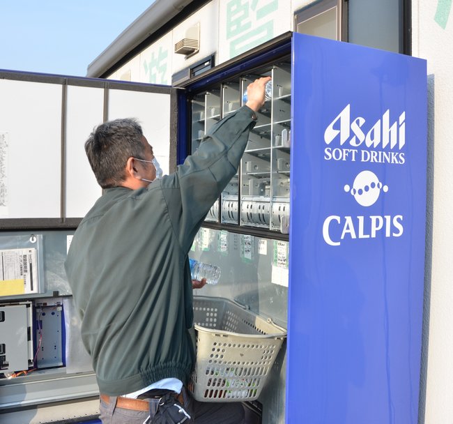 飲料自動販売機に飲料品を補充する、自販機オペレーターの従業員＝松江市東朝日町