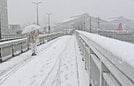 雪が積もった道を歩く通行人＝２１日午前１０時２５分、松江市西川津町、くにびき大橋