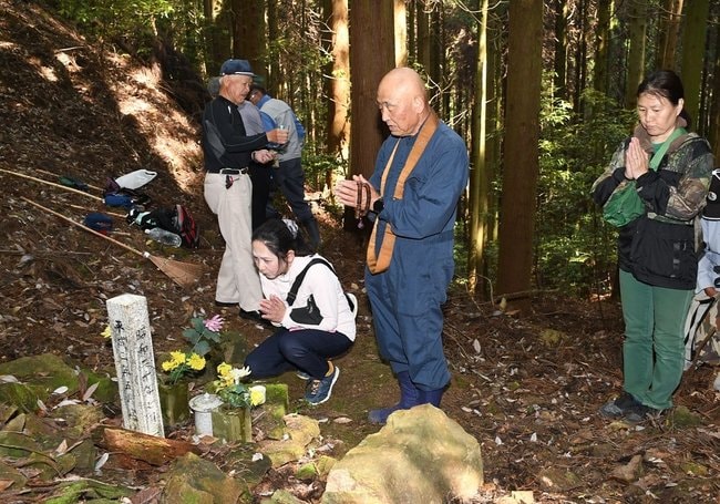 終戦直前に出雲市大社町の北山に墜落した日本海軍攻撃機の慰霊碑に手を合わせる参加者。この後「海ゆかば」を合唱した=6月7日、出雲市内