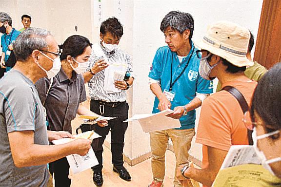 ボランティア説明会で競技委員（手前左から４人目）から役割などを聞く参加者＝米子市皆生温泉３丁目、市観光センター