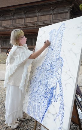 青色のマーカーペンで昇り竜を描く青已はなねさん=出雲市大社町杵築東、出雲大社
