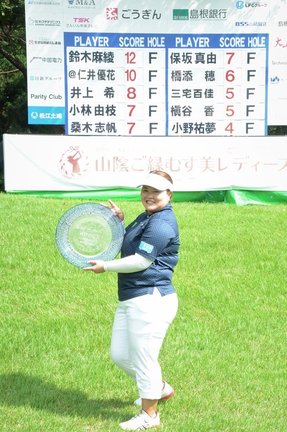 スコアボードの前で優勝トロフィーのガラス製プレートを持つ鈴木麻綾＝大山平原ゴルフクラブ