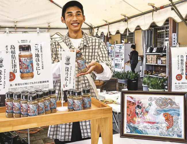 タイを釣り上げる「恵比寿」の絵がラベルに採用された商品をＰＲする佐々木和仁さん＝江津市後地町、道の駅「サンピコごうつ」