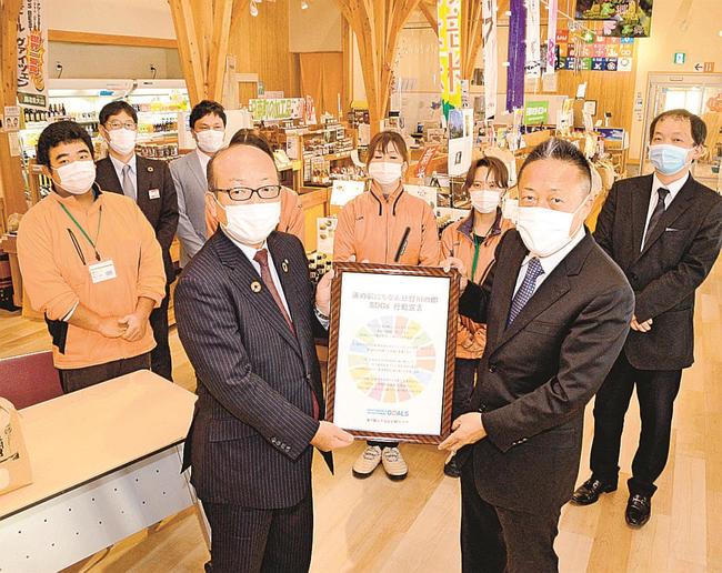 鳥取県日南町の中村英明町長（左）に行動宣言の額を手渡す和泉享社長＝同町生山、にちなん日野川の郷