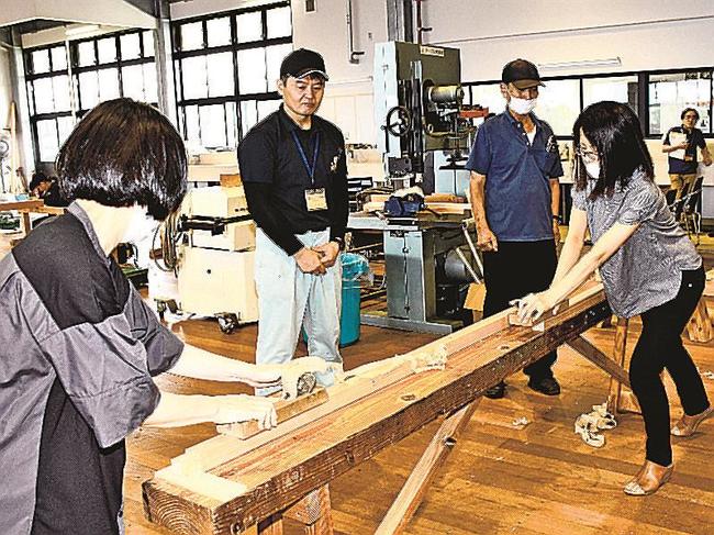 職業訓練指導員(左から2人目)から教わりながらかんなで木を削る参加者=益田市高津4丁目、島根県立西部高等技術校