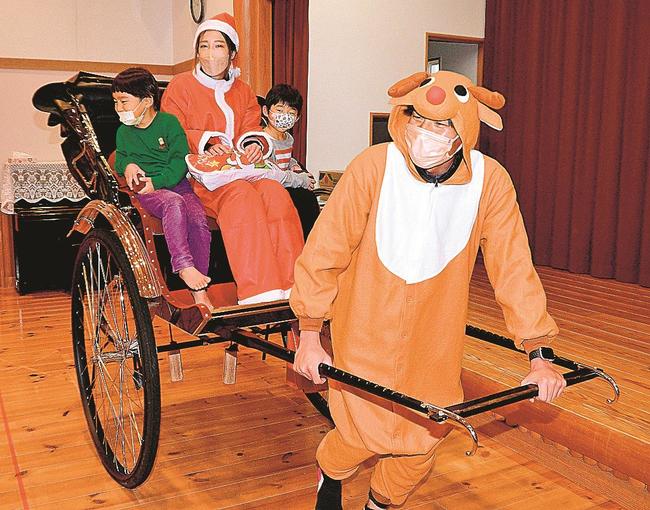 トナカイ姿の糸賀太郎代表が引く人力車に乗り、喜ぶ園児=出雲市大社町杵築南の大社保育園