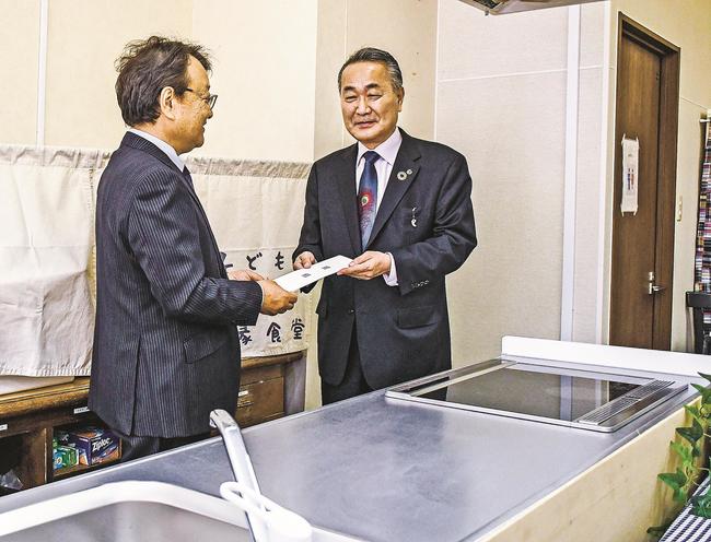 新設したシステムキッチンの前で目録を手渡す松江土建の平塚智朗社長（右）＝松江市殿町、殿まちギャラリー