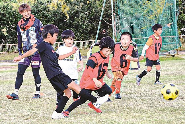 選手（左）が見守る中、ミニゲームを楽しむ子どもたち＝安来市吉岡町、安来運動公園陸上競技場