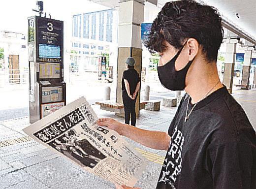 森英恵さんの訃報を伝える号外に目を落とす市民＝松江市朝日町、ＪＲ松江駅