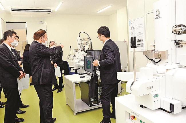 素材試験などに使う最先端機器を見学する関係者＝松江市西川津町、次世代たたら協創センター