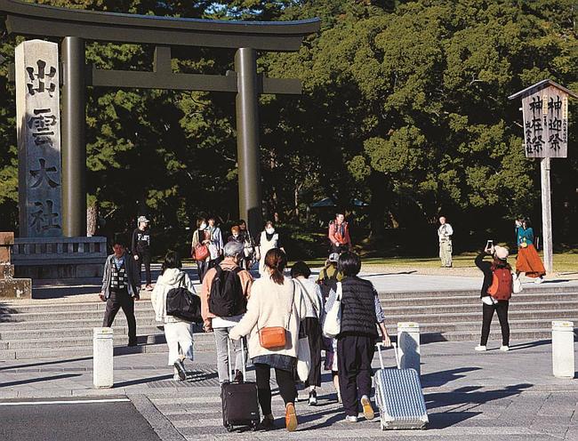 スーツケースや大きな荷物を持ったまま出雲大社に向かう観光客＝出雲市大社町