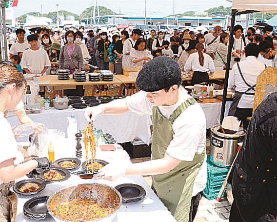 大勢の客が並ぶ前で料理を盛り付けるスタッフ＝浜田市原井町、はまだお魚市場